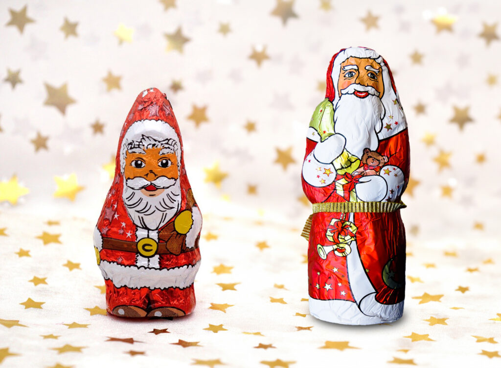 Two chocolate Santa Clauses in front of a white background that has lots of golden stars on it. Raman chocolate quality analysis was able to tell which one was the best. 